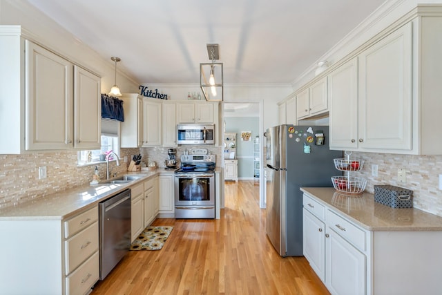 kitchen featuring sink, light hardwood / wood-style flooring, appliances with stainless steel finishes, hanging light fixtures, and decorative backsplash