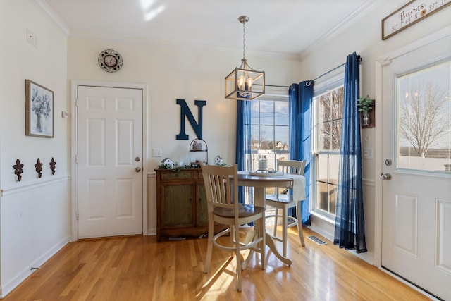 dining room with an inviting chandelier, hardwood / wood-style floors, and crown molding