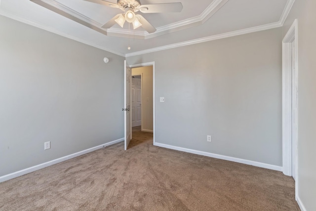 carpeted spare room with ornamental molding, a raised ceiling, and ceiling fan