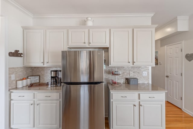 kitchen with white cabinetry, stainless steel fridge, and tasteful backsplash