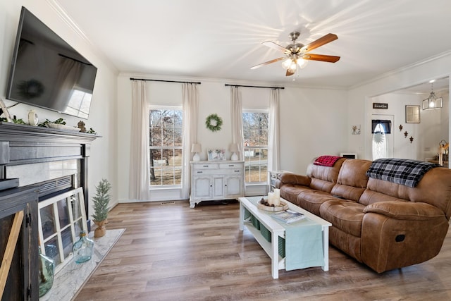 living room with hardwood / wood-style flooring, ornamental molding, a premium fireplace, and ceiling fan