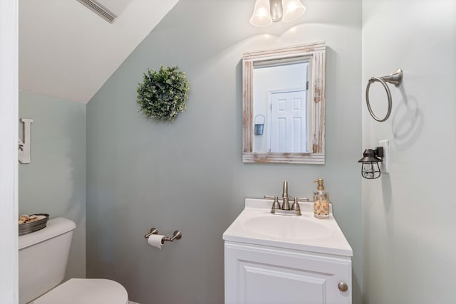 bathroom featuring vanity, vaulted ceiling, and toilet