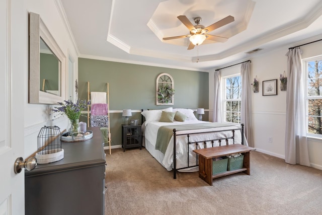 bedroom featuring crown molding, ceiling fan, a tray ceiling, and light colored carpet