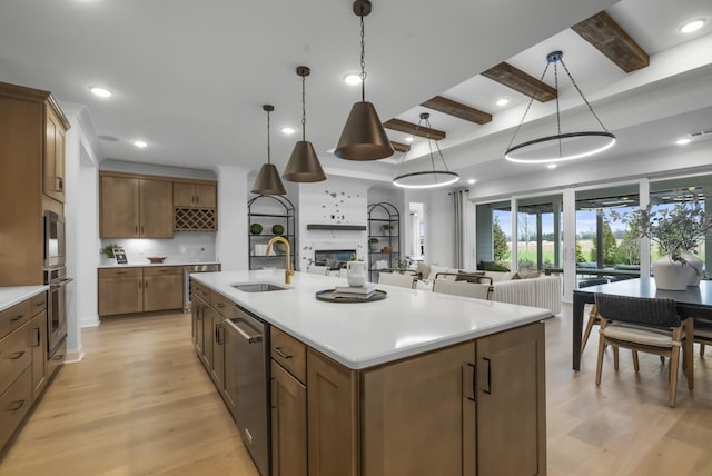 kitchen featuring a large island, appliances with stainless steel finishes, decorative light fixtures, beamed ceiling, and light wood-type flooring