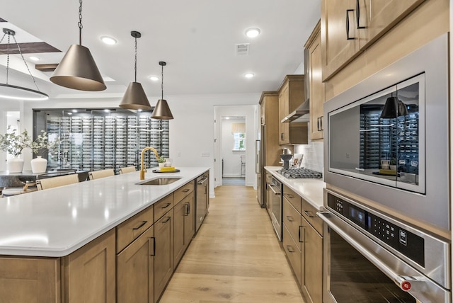 kitchen featuring pendant lighting, sink, stainless steel appliances, a spacious island, and light wood-type flooring