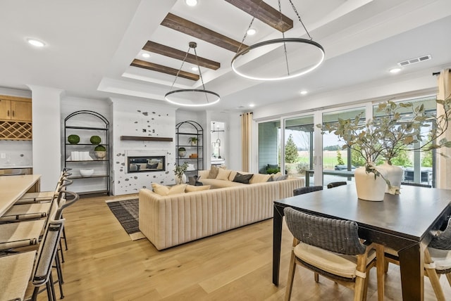 living room featuring a raised ceiling, beamed ceiling, and light hardwood / wood-style flooring