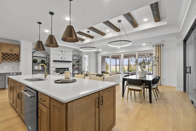 kitchen featuring light hardwood / wood-style flooring, sink, hanging light fixtures, and a large island with sink