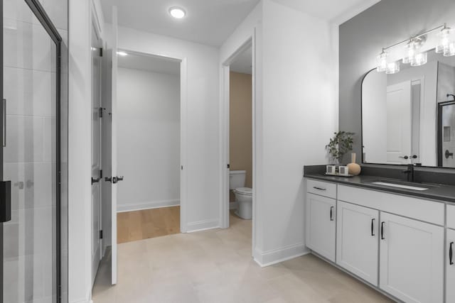 bathroom with walk in shower, vanity, toilet, and tile patterned flooring