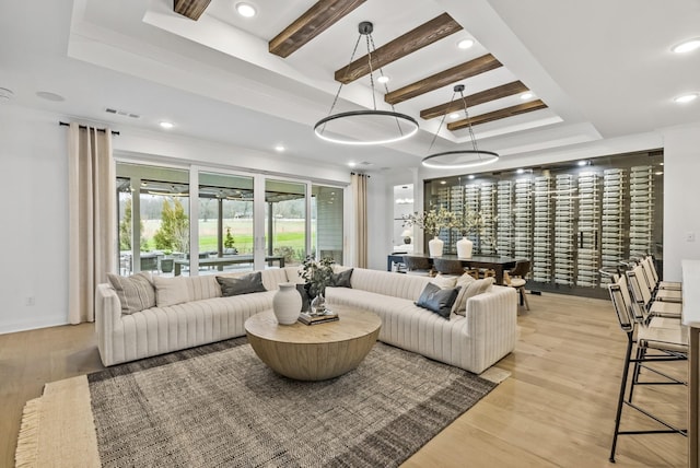 living room featuring a raised ceiling, light hardwood / wood-style floors, and beamed ceiling