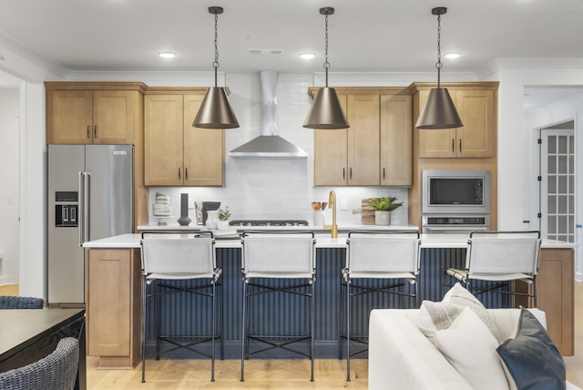 kitchen with crown molding, decorative light fixtures, stainless steel appliances, and wall chimney exhaust hood