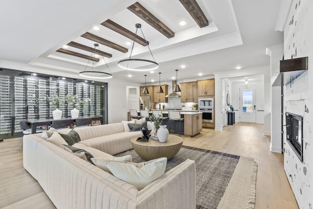 living room featuring a wealth of natural light, light hardwood / wood-style flooring, a raised ceiling, and a stone fireplace