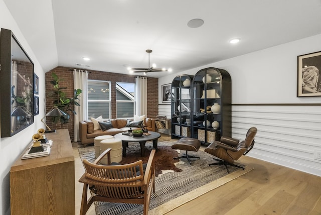 interior space featuring lofted ceiling, brick wall, a chandelier, and hardwood / wood-style floors