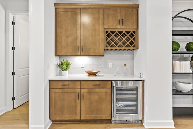 bar featuring wine cooler, light hardwood / wood-style floors, and decorative backsplash