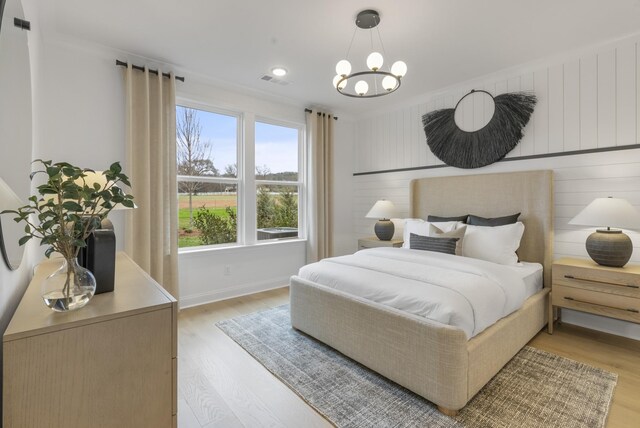 bedroom with crown molding, an inviting chandelier, and light hardwood / wood-style floors