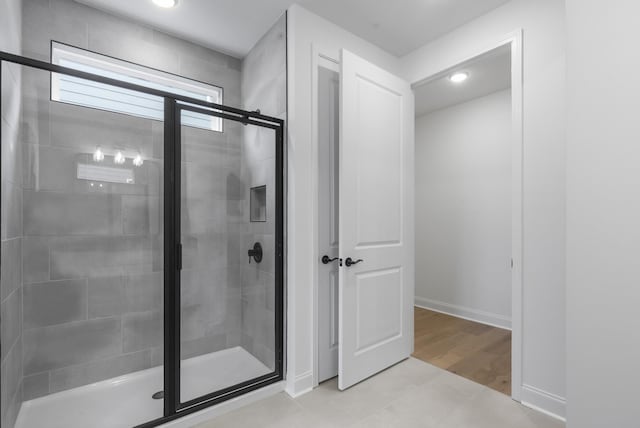 bathroom with a shower with door and tile patterned floors