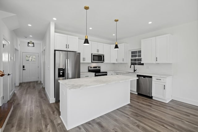 kitchen featuring sink, decorative light fixtures, a center island, stainless steel appliances, and white cabinets