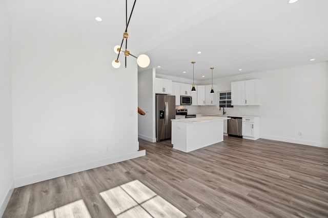 kitchen featuring sink, a center island, pendant lighting, stainless steel appliances, and white cabinets