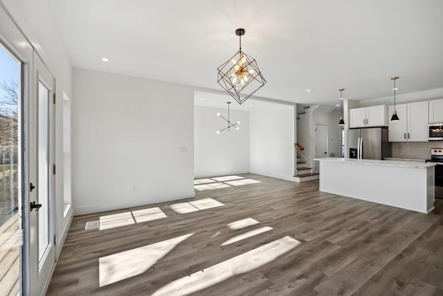 kitchen with appliances with stainless steel finishes, an inviting chandelier, decorative backsplash, white cabinets, and decorative light fixtures