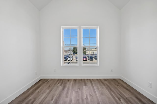 spare room featuring vaulted ceiling and light wood-type flooring