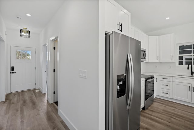 kitchen with white cabinetry, appliances with stainless steel finishes, sink, and hardwood / wood-style floors