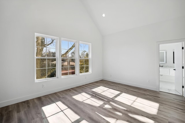 unfurnished room with hardwood / wood-style floors and high vaulted ceiling