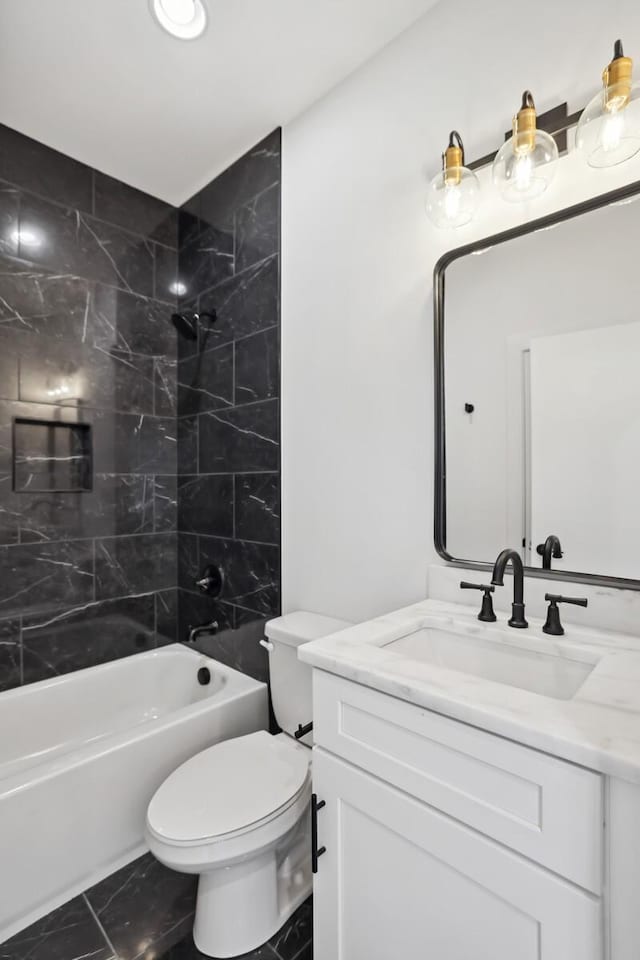 full bathroom featuring tiled shower / bath, vanity, and toilet