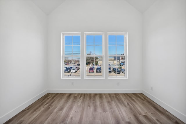 empty room with vaulted ceiling and light wood-type flooring