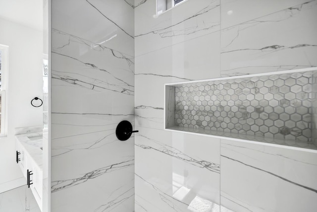 bathroom with a tile shower and vanity