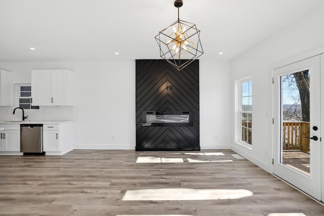 unfurnished dining area with an inviting chandelier, sink, and light hardwood / wood-style flooring