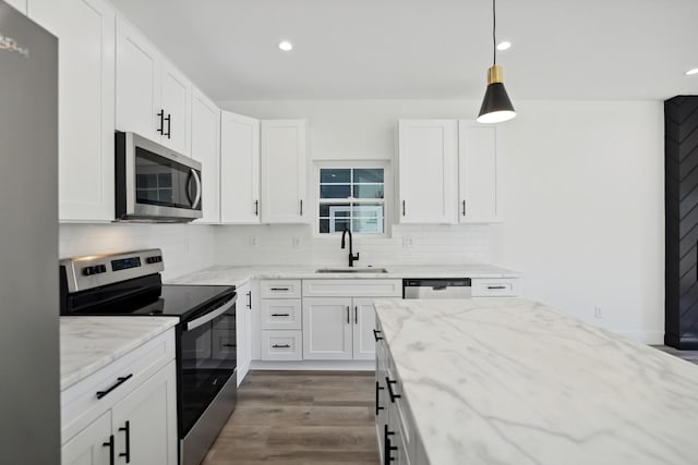 kitchen with sink, hanging light fixtures, stainless steel appliances, light stone counters, and white cabinets