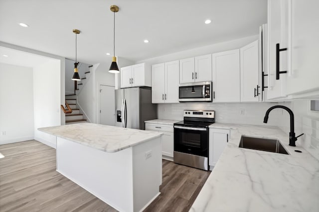 kitchen with light stone countertops, appliances with stainless steel finishes, and white cabinets