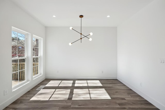 unfurnished dining area featuring dark wood-type flooring and a chandelier