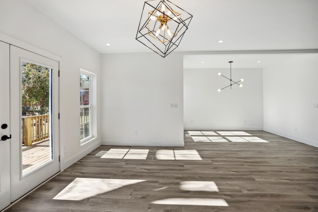 unfurnished dining area with a notable chandelier and dark hardwood / wood-style flooring