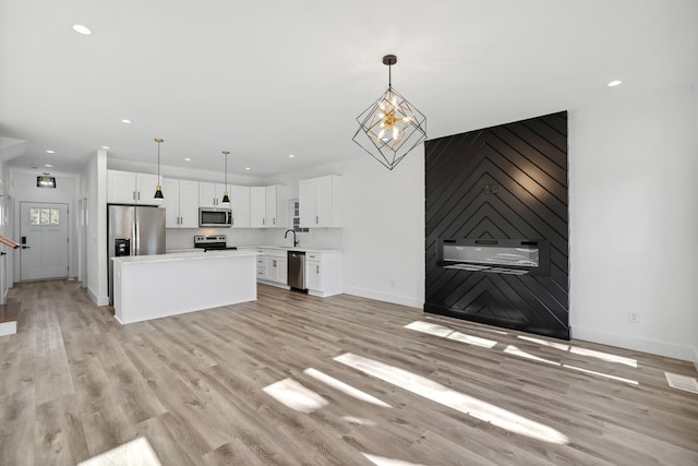 unfurnished living room featuring sink, an inviting chandelier, and light wood-type flooring