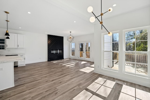 unfurnished living room featuring light hardwood / wood-style floors, french doors, and a chandelier