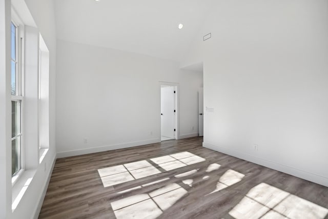 empty room with high vaulted ceiling and hardwood / wood-style floors