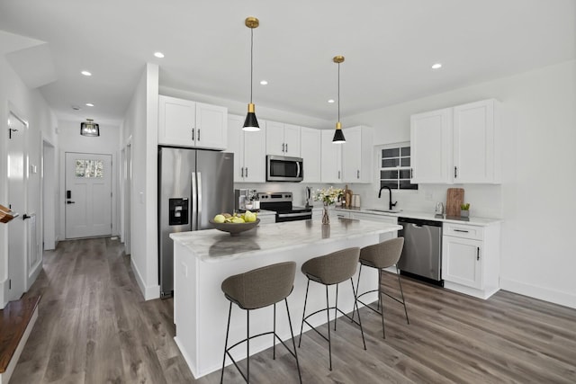 kitchen featuring decorative light fixtures, sink, white cabinets, a center island, and stainless steel appliances