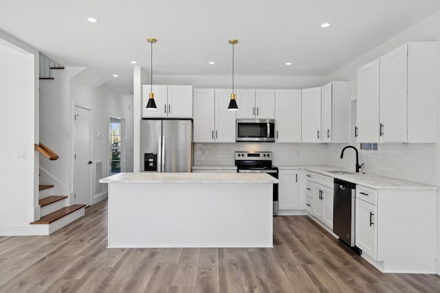 kitchen featuring a kitchen island, decorative light fixtures, sink, white cabinets, and stainless steel appliances