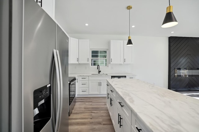 kitchen featuring white cabinetry, appliances with stainless steel finishes, light stone counters, and hanging light fixtures