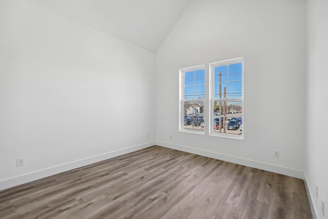 empty room featuring high vaulted ceiling and light hardwood / wood-style flooring