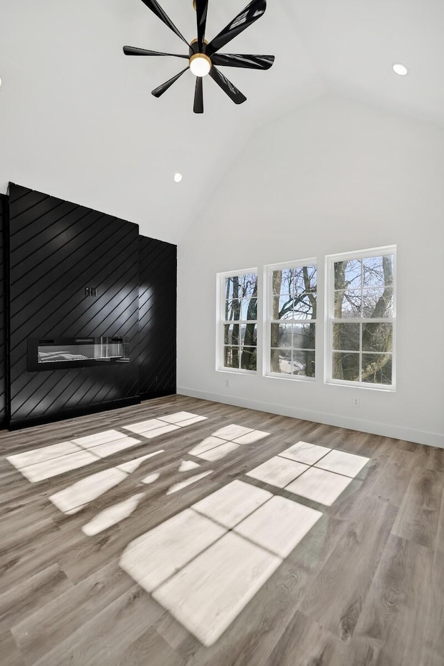 unfurnished living room with ceiling fan, light hardwood / wood-style flooring, high vaulted ceiling, and a healthy amount of sunlight