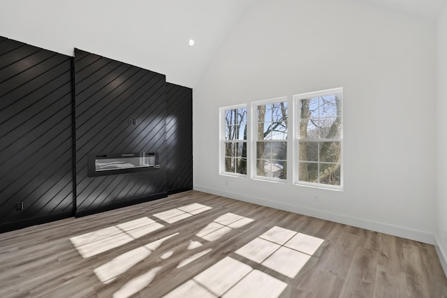 empty room with high vaulted ceiling and light wood-type flooring