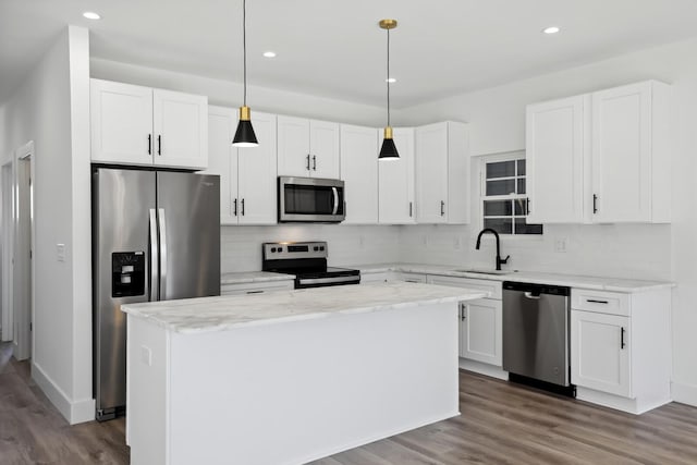 kitchen with stainless steel appliances, decorative light fixtures, a center island, and sink