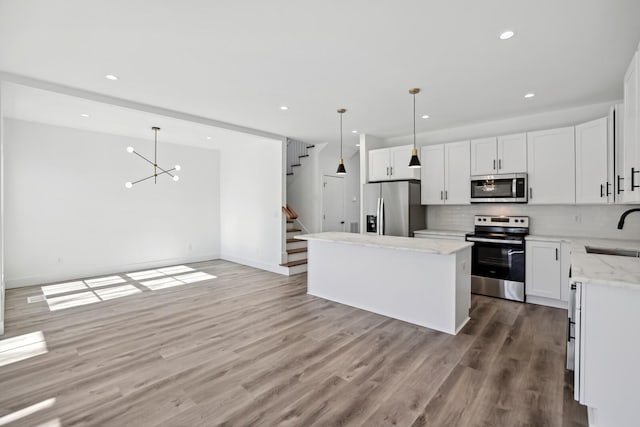 kitchen featuring white cabinetry, hanging light fixtures, stainless steel appliances, and sink