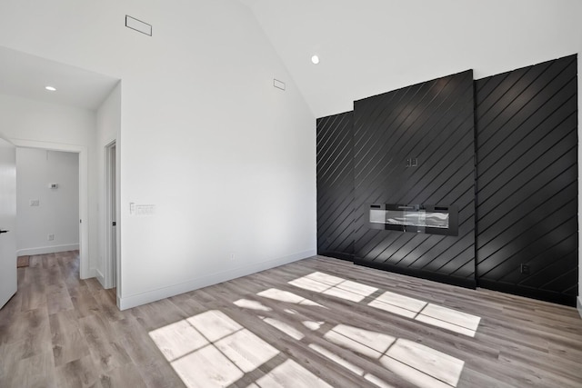 empty room featuring high vaulted ceiling and light hardwood / wood-style floors