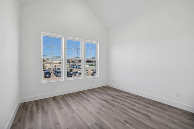 spare room with light wood-type flooring and high vaulted ceiling