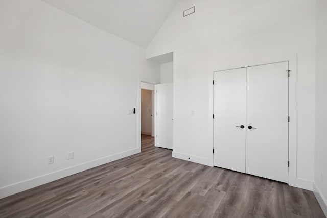 unfurnished bedroom with light hardwood / wood-style floors, high vaulted ceiling, and a closet