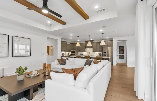 living room featuring ceiling fan, sink, beam ceiling, and light hardwood / wood-style floors