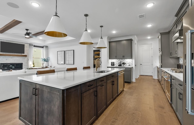 kitchen featuring hanging light fixtures, an island with sink, and light wood-type flooring