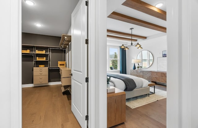 bedroom with beamed ceiling, hardwood / wood-style floors, and a closet